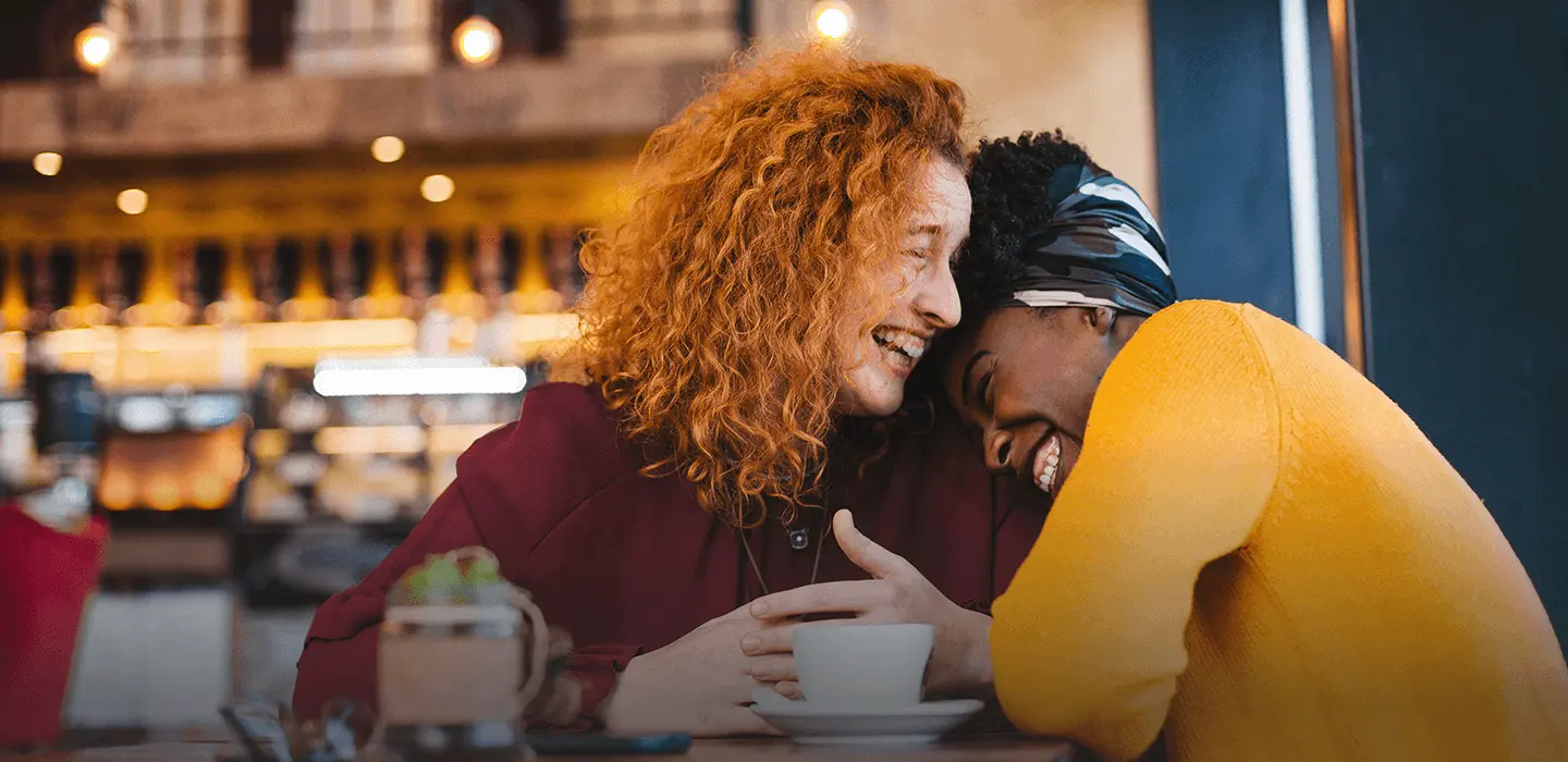 A specialty pharmacy patient and her best friend laughing together in a café