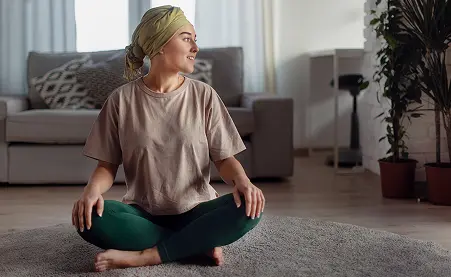 A specialty pharmacy patient sits cross-legged, looking peacefully out the window